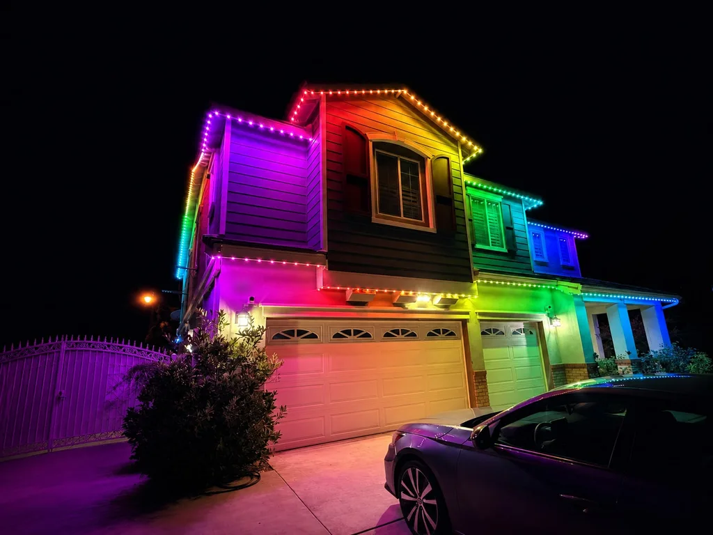 Rendering of a two-story house at night with its rooflines and trim lit in a full rainbow of colors